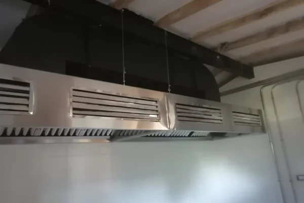 Campana de isla tipo II suspendida sobre cocina abierta de restaurante
